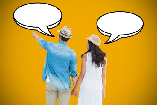 Happy hipster couple holding hands and looking against yellow background with vignette