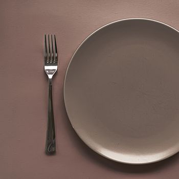 Empty plate and cutlery as mockup set on brown background, top tableware for chef table decor and menu branding design