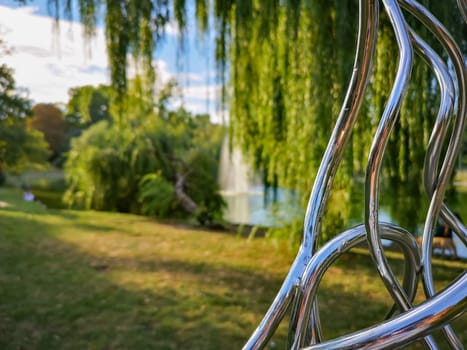 Part of chrome metal construction in park with colorful park in background