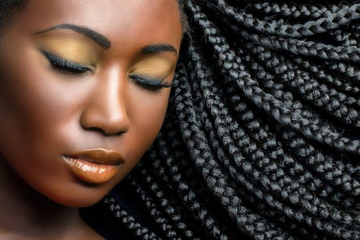 Extreme close up beauty cosmetic portrait of young african woman  with eyes closed.Girl wearing professional make up showing black braided hairstyle.