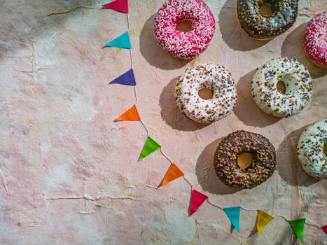 Flat lay of colorful donuts with colorful triangles on light fabric background