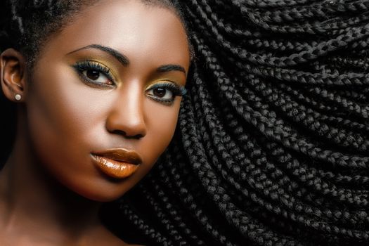 Extreme close up beauty portrait of young african woman showing long braided hair next to face.