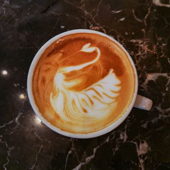 Swan latte art on coffee on stone table