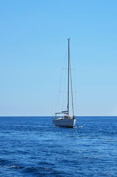 Tranquil seascape with calm sea water ripples and waves and sail yacht under clear day blue sky, high angle view