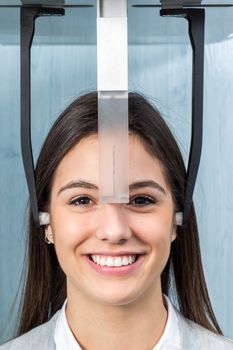 Close up face shot of girl taking dental x-ray on cephalometric panorama machine in clinic.