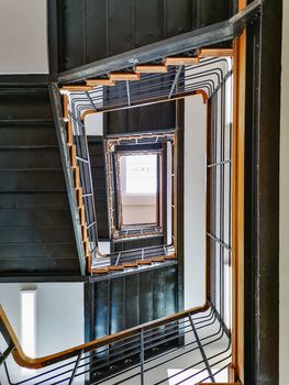 Lookup to spiral rectangle metal staircase with window on top