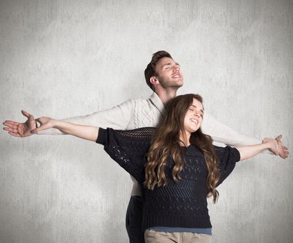Romantic young couple with arms out against weathered surface 