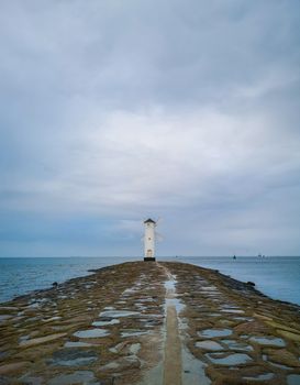 White Windmill at end of coast full of puddles near Baltic sea in Swinoujscie