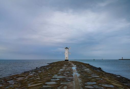 White Windmill at end of coast full of puddles near Baltic sea in Swinoujscie