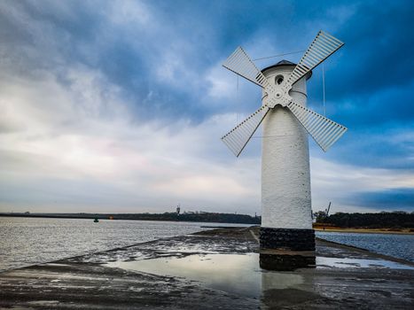 White Windmill at end of coast full of puddles near Baltic sea in Swinoujscie