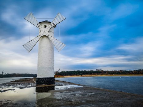 White Windmill at end of coast full of puddles near Baltic sea in Swinoujscie