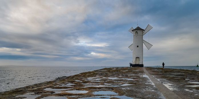 White Windmill at end of coast full of puddles near Baltic sea in Swinoujscie