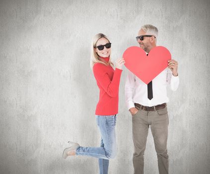 Cool couple holding a red heart together against weathered surface 