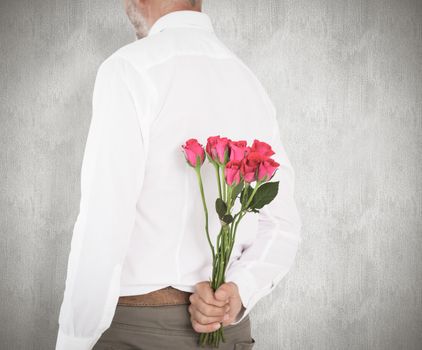 Man holding bouquet of roses behind back against weathered surface 
