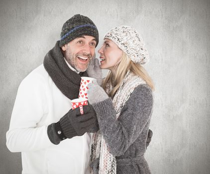 Happy couple in winter fashion holding mugs against weathered surface 