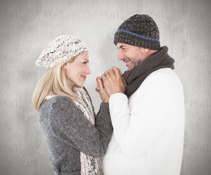 Couple in winter fashion embracing against weathered surface 