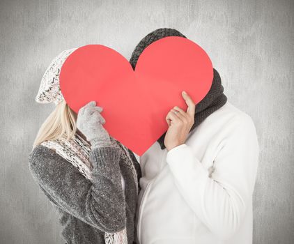 Couple in winter fashion posing with heart shape against weathered surface 
