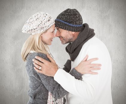 Happy couple in winter fashion embracing against weathered surface 