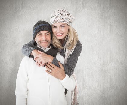 Happy couple in winter fashion embracing against weathered surface 