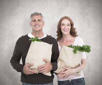 Casual couple holding grocery bags against white background
