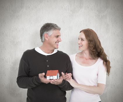 Casual couple holding small house against white background