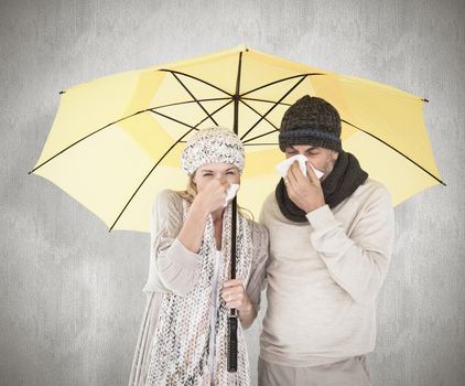 Couple in winter fashion sneezing under umbrella against white background