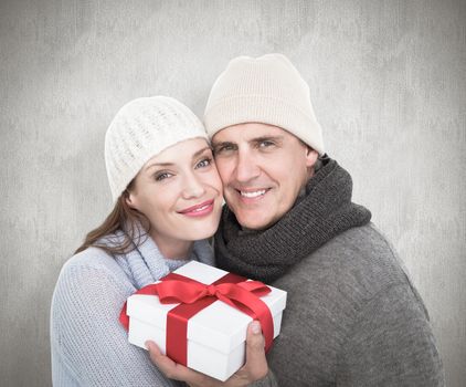 Casual couple in warm clothing holding gift against white background