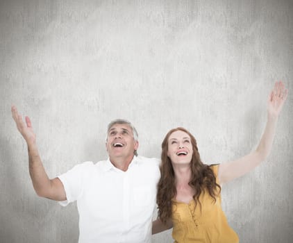 Casual couple smiling with arms raised against white background