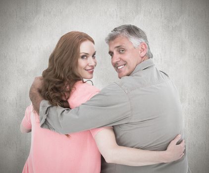 Casual couple standing arms around against white background