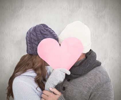Couple in warm clothing holding heart against white background