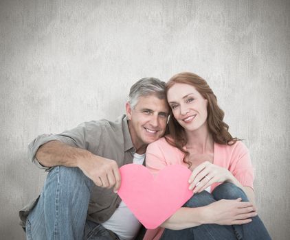 Casual couple holding pink heart against white background