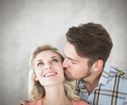 Handsome man kissing girlfriend on cheek against white background