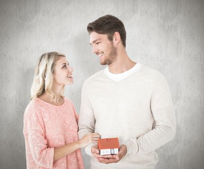 Attractive couple holding miniature house model against white background