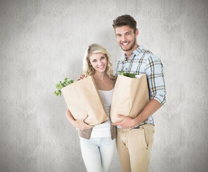 Attractive couple holding their grocery bags against white background