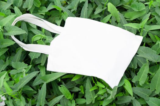 Closeup white bag canvas fabric on green grass background, Save the world concept