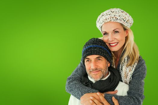 Happy couple in winter fashion embracing against green vignette