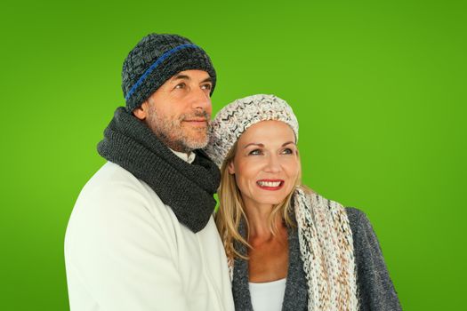 Happy couple in winter fashion embracing against green vignette