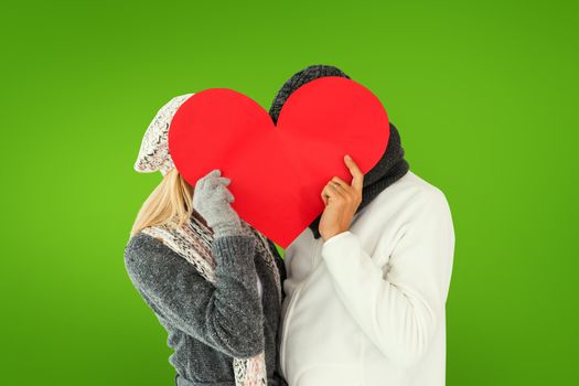 Couple in winter fashion posing with heart shape against green vignette