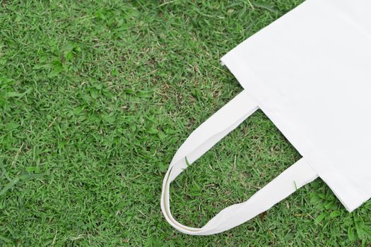 Closeup white bag canvas fabric on green grass background, Save the world concept