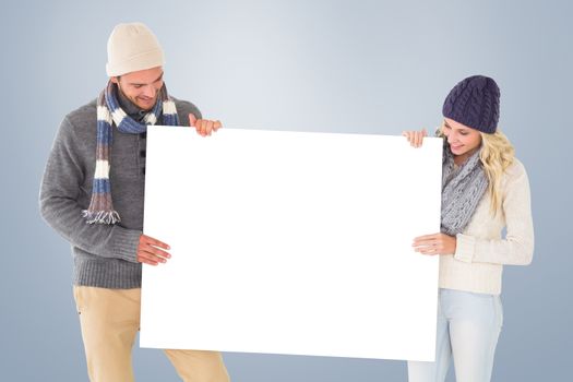 Attractive couple in winter fashion showing poster against grey vignette