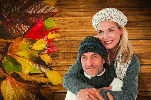 Happy couple in winter fashion embracing against wooden table with autumn leaves