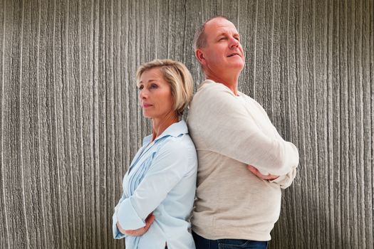 Mature couple standing and thinking against wooden planks