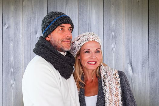 Happy couple in winter fashion embracing against wooden planks