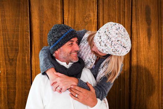 Happy couple in winter fashion embracing against overhead of wooden planks