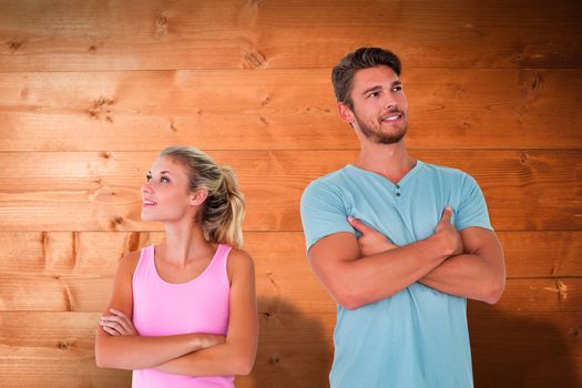 Young couple posing with arms crossed against overhead of wooden planks