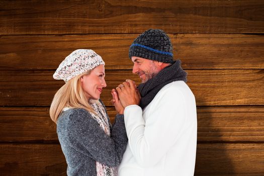 Couple in winter fashion embracing against overhead of wooden planks