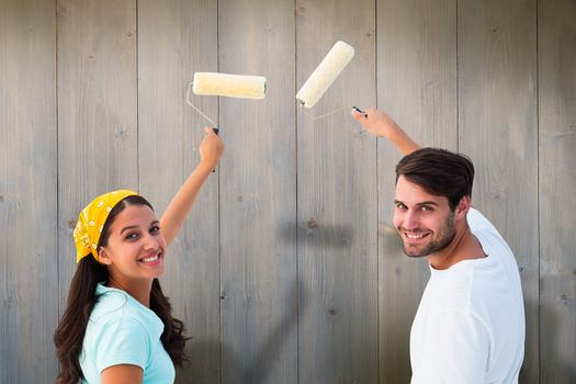 Happy young couple painting together against pale grey wooden planks