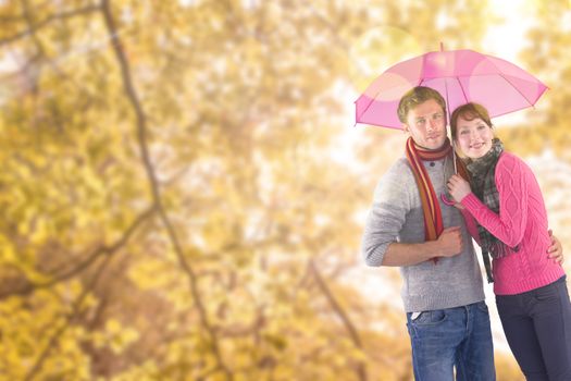 Couple standing underneath an umbrella against tranquil autumn scene in forest