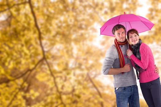 Couple standing underneath an umbrella against tranquil autumn scene in forest