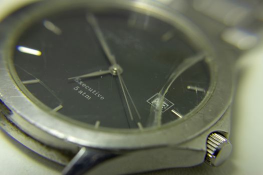 Broken wrist watch, with its glass shattered and damaged bracelet